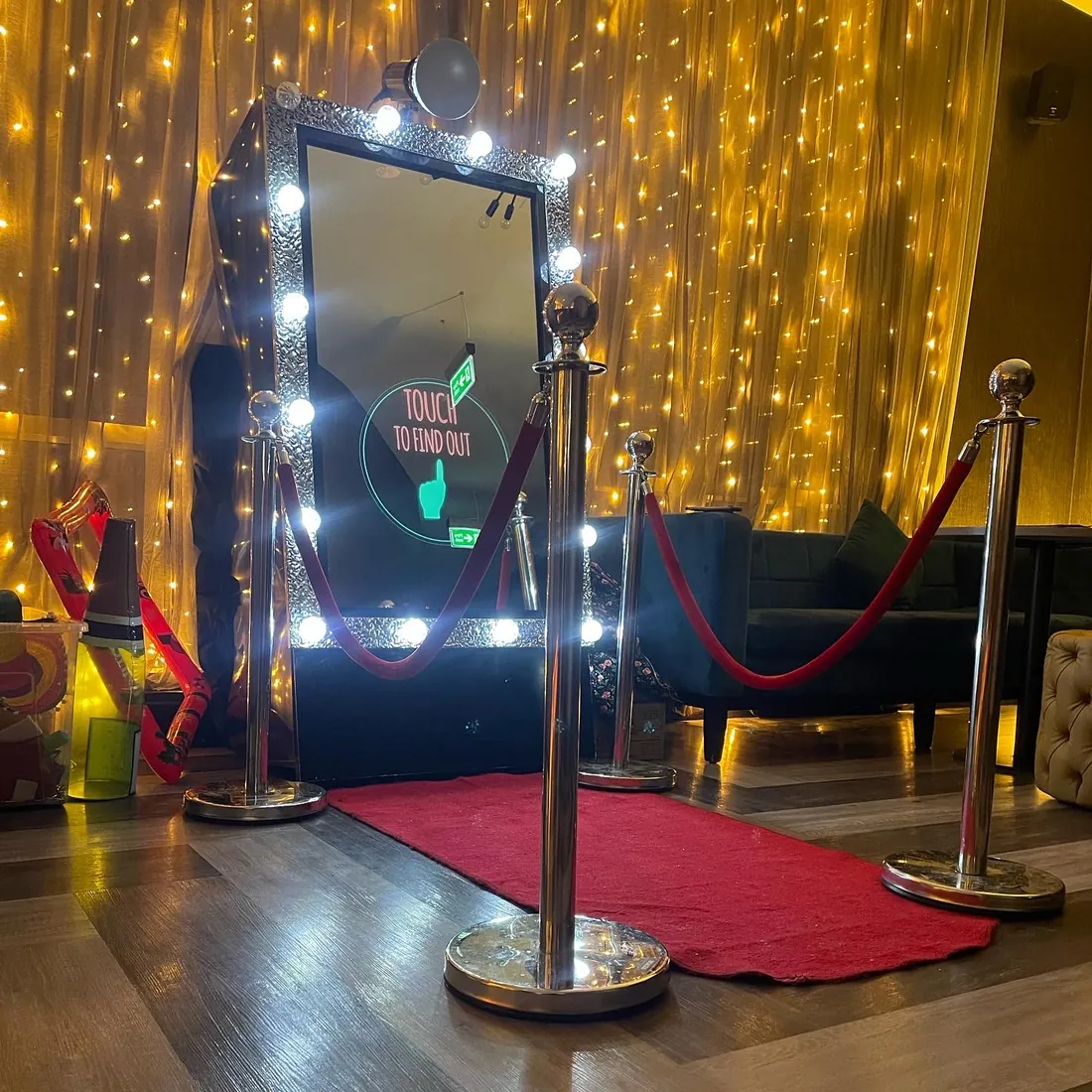 The Magic Mirror photo booth set up with a red carpet and fairy-light backdrop